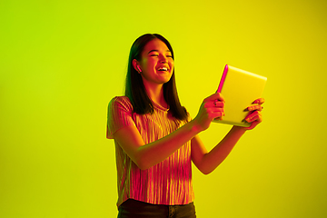 Image showing Beautiful girl\'s facial expression in neon light on yellow studio background