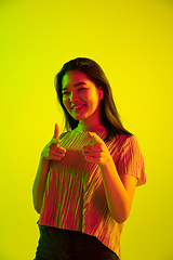 Image showing Beautiful girl\'s facial expression in neon light on yellow studio background