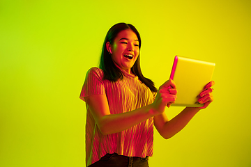 Image showing Beautiful girl\'s facial expression in neon light on yellow studio background