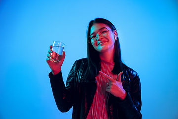 Image showing Beautiful girl\'s facial expression in neon light on blue studio background