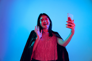 Image showing Beautiful girl\'s facial expression in neon light on blue studio background