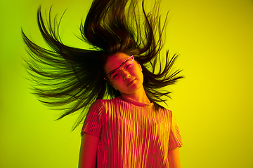 Image showing Beautiful girl\'s facial expression in neon light on yellow studio background