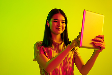 Image showing Beautiful girl\'s facial expression in neon light on yellow studio background