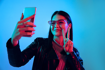 Image showing Beautiful girl\'s facial expression in neon light on blue studio background