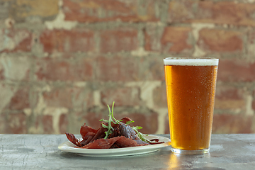 Image showing Glass of light beer on the stone table and brick\'s background