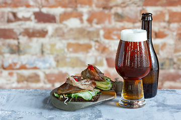 Image showing Glass of beer on the stone table and brick\'s background