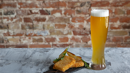 Image showing Glass of light beer on the stone table and brick\'s background