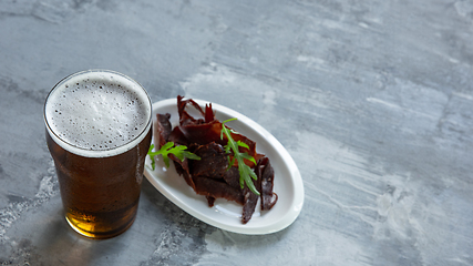 Image showing Glass of beer on the stone table and brick\'s background