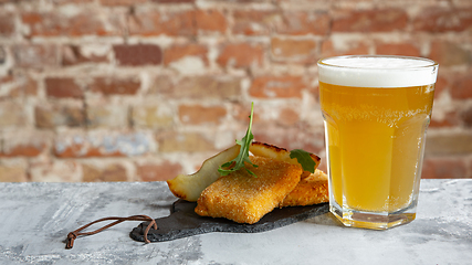 Image showing Glass of light beer on the stone table and brick\'s background