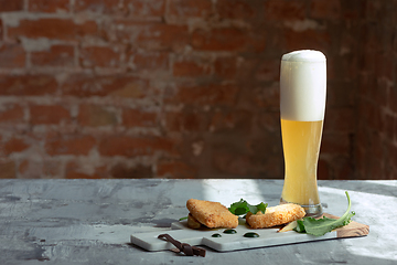 Image showing Glass of light beer on the stone table and brick\'s background