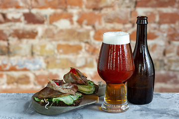 Image showing Glass of beer on the stone table and brick\'s background