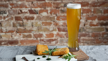Image showing Glass of beer on the stone table and brick\'s background
