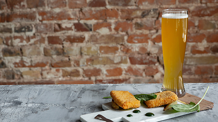 Image showing Glass of light beer on the stone table and brick\'s background