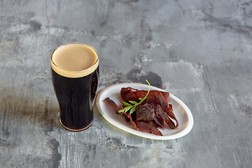 Image showing Glass of dark beer on the stone table and brick\'s background