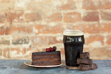 Image showing Glass of dark beer on the stone table and brick\'s background