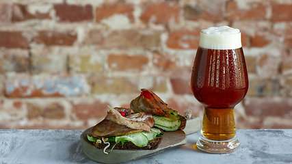 Image showing Glass of beer on the stone table and brick\'s background