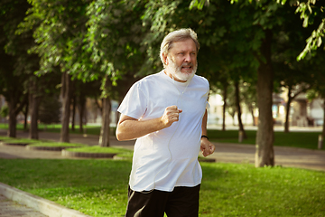 Image showing Senior man as runner with armband or fitness tracker at the city\'s street