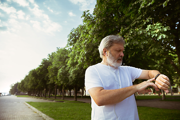 Image showing Senior man as runner with armband or fitness tracker at the city\'s street