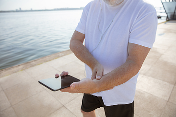 Image showing Senior man as runner with armband or fitness tracker at the riverside