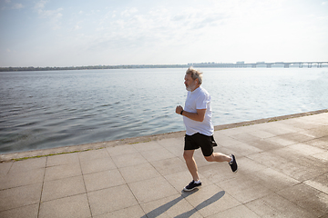 Image showing Senior man as runner with armband or fitness tracker at the riverside