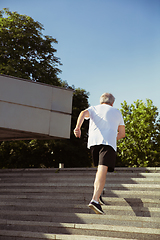 Image showing Senior man as runner with armband or fitness tracker at the city\'s street