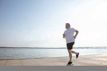 Image showing Senior man as runner with armband or fitness tracker at the riverside