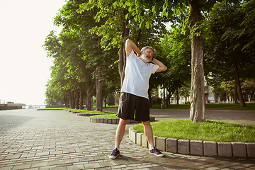 Image showing Senior man as runner with armband or fitness tracker at the city\'s street