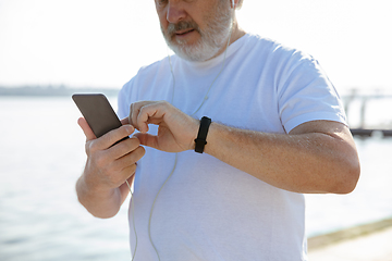 Image showing Senior man as runner with armband or fitness tracker at the riverside