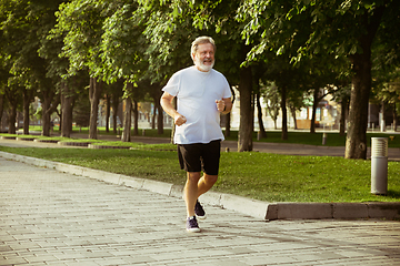 Image showing Senior man as runner with armband or fitness tracker at the city\'s street