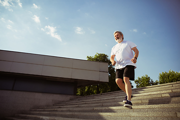 Image showing Senior man as runner with armband or fitness tracker at the city\'s street