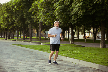 Image showing Senior man as runner with armband or fitness tracker at the city\'s street