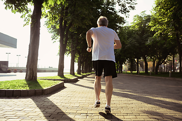 Image showing Senior man as runner with armband or fitness tracker at the city\'s street