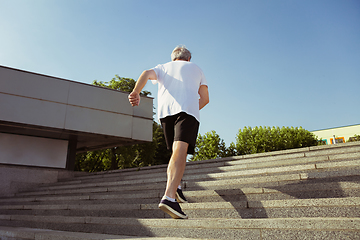 Image showing Senior man as runner with armband or fitness tracker at the city\'s street