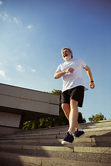 Image showing Senior man as runner with armband or fitness tracker at the city\'s street