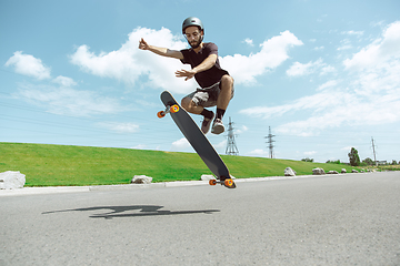 Image showing Skateboarder doing a trick at the city\'s street in sunny day