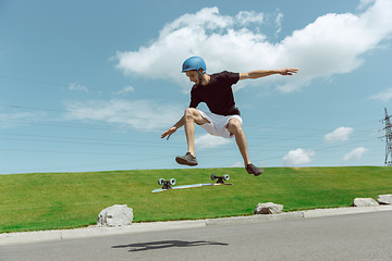 Image showing Skateboarder doing a trick at the city\'s street in sunny day