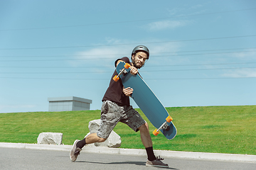 Image showing Skateboarder doing a trick at the city\'s street in sunny day