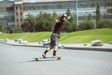 Image showing Skateboarder doing a trick at the city\'s street in sunny day