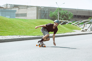 Image showing Skateboarder doing a trick at the city\'s street in sunny day