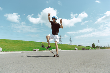 Image showing Skateboarder doing a trick at the city\'s street in sunny day