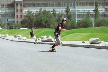 Image showing Skateboarders doing a trick at the city\'s street in sunny day