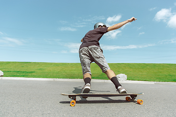 Image showing Skateboarder doing a trick at the city\'s street in sunny day