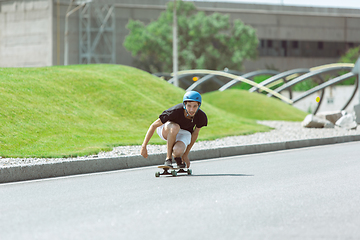 Image showing Skateboarder doing a trick at the city\'s street in sunny day