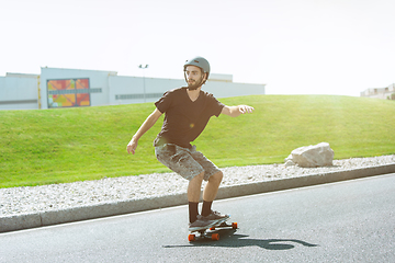 Image showing Skateboarder doing a trick at the city\'s street in sunny day