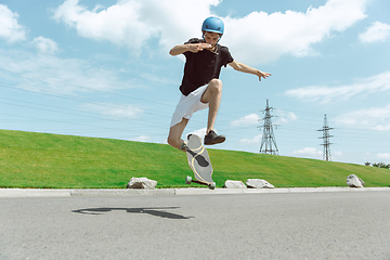 Image showing Skateboarder doing a trick at the city\'s street in sunny day