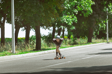 Image showing Skateboarder doing a trick at the city\'s street in sunny day