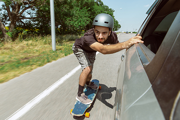 Image showing Skateboarder doing a trick at the city\'s street in sunny day