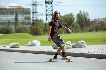 Image showing Skateboarder doing a trick at the city\'s street in sunny day