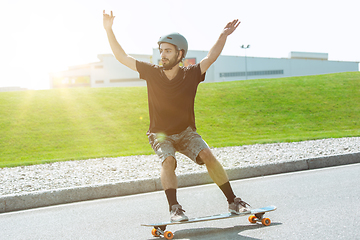 Image showing Skateboarder doing a trick at the city\'s street in sunny day