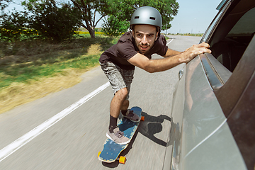 Image showing Skateboarder doing a trick at the city\'s street in sunny day